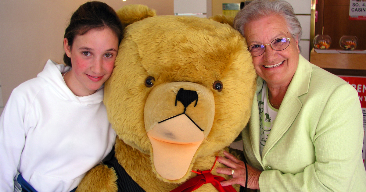 Junges Mädchen und ihre Oma posieren mit Riesenteddy