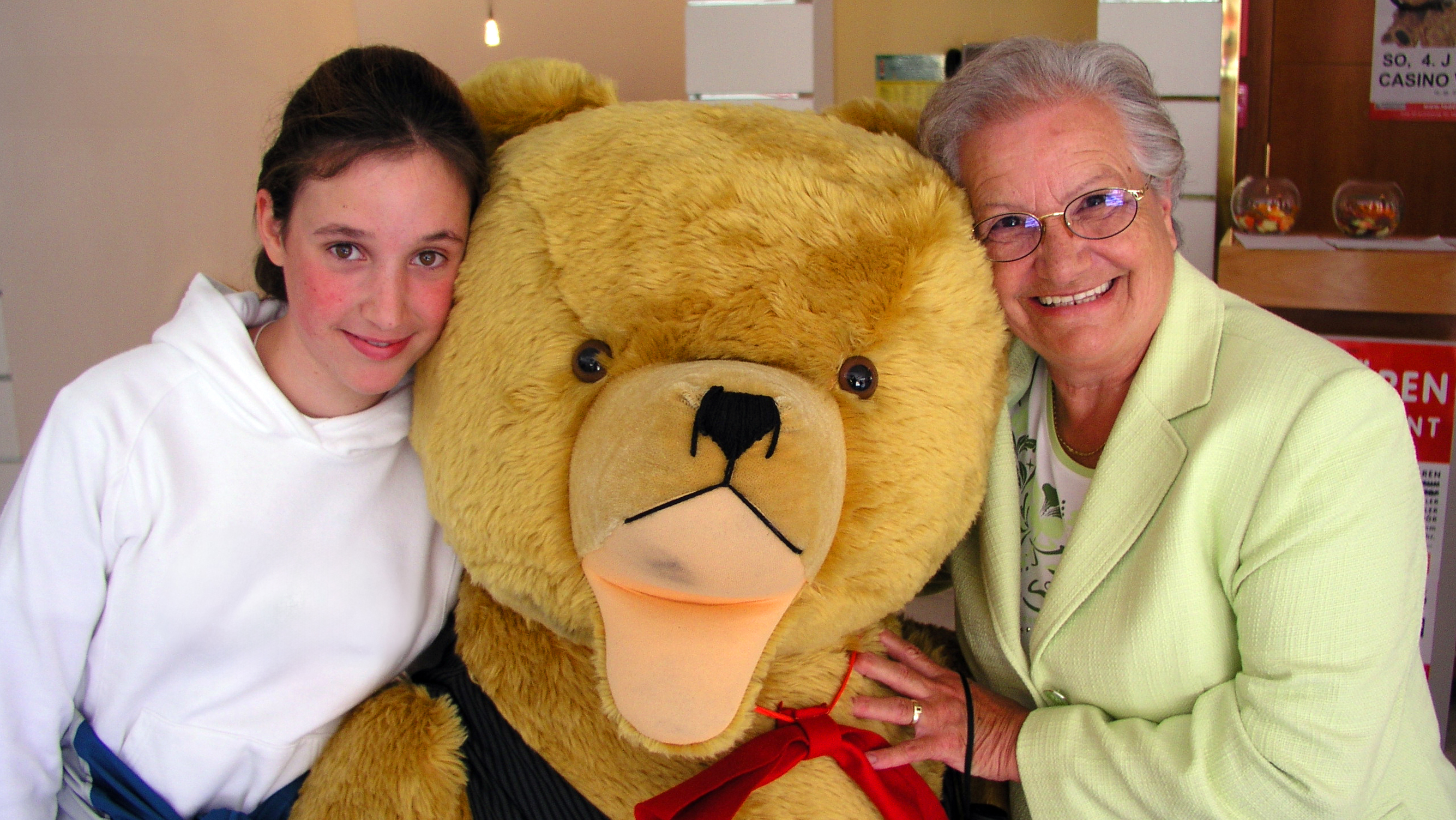 Junges Mädchen und ihre Oma posieren mit Riesenteddy